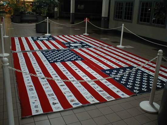 Two of the 9-11 memorial quilts laid flat on a mall floor inside a rope barrier