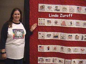 Linda Zuroff standing beside one of the flag quilts at the Hershey show